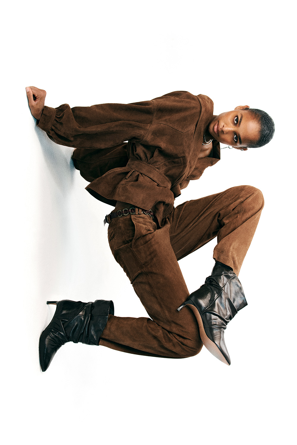 The model is wearing a brown suede jacket